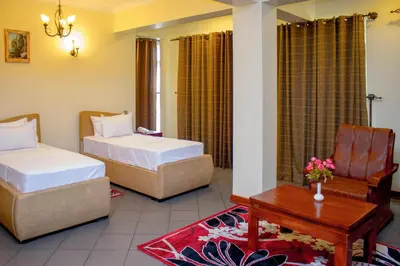 a hotel room with two beds and a desk at seven skies hotel in Arusha