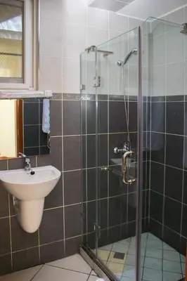 a bathroom with a shower with a sink and a toilet at seven skies hotel in Arusha