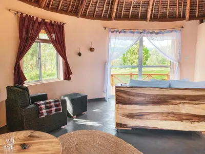 a room with a bed and a table and windows at Foresight Eco Lodge & Safari in Karatu