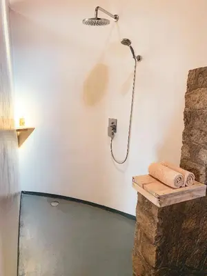 a shower in a bathroom with a stone wall at Foresight Eco Lodge & Safari in Karatu