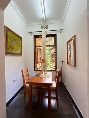 a dining room with a table and chairs and a window at Sophie Homestay in Moshi