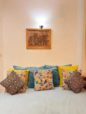 a couch with pillows and a picture on the wall at Sophie Homestay in Moshi