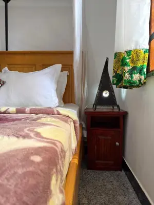 a bedroom with two beds and a table with a lamp at Sophie Homestay in Moshi