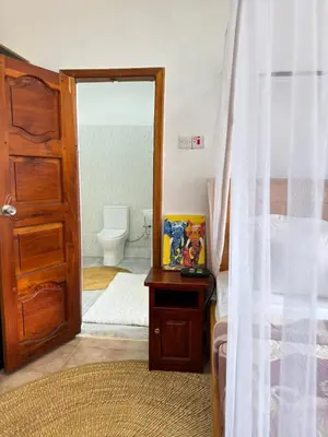 a bedroom with a door open to a bathroom at Sophie Homestay in Moshi