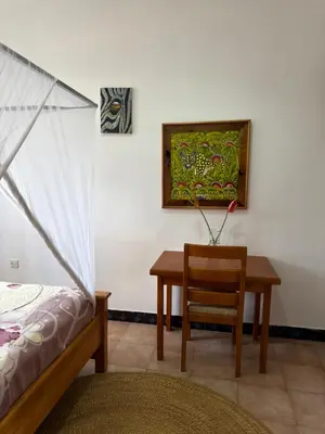 a bedroom with a table and a bed and a painting at Sophie Homestay in Moshi