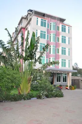 a pink and white building with plants in front of it at Elanacha Hotel in Arusha