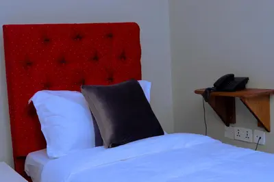 a bedroom with a bed with a red headboard and a phone at Elanacha Hotel in Arusha