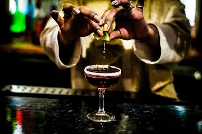 a person pouring a drink into a wine glass at Elanacha Hotel in Arusha