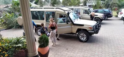 a group of people standing next to a white vehicle at Elanacha Hotel in Arusha