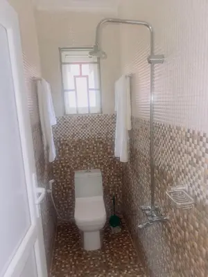 a bathroom with a toilet and a shower with a window at Mkomazi Hotels and Camps in Hegoma