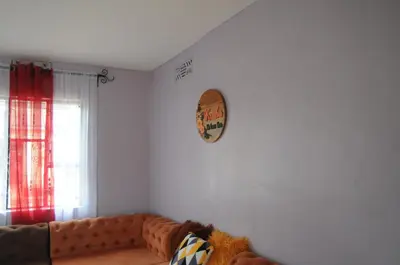 a living room with a couch and a clock on the wall at Hakuna Matata Cozy Apartment in Karatu