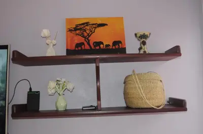 a shelf with a picture of elephants and a basket on it at Hakuna Matata Cozy Apartment in Karatu