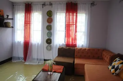 a living room with a couch and two windows at Hakuna Matata Cozy Apartment in Karatu