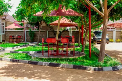a group of red chairs sitting under an umbrella at Randa Cottages Moshi in Kirua