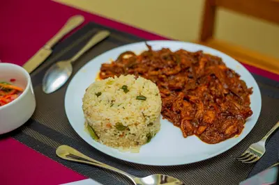 a white plate of food with rice and meat at Randa Cottages Moshi in Kirua