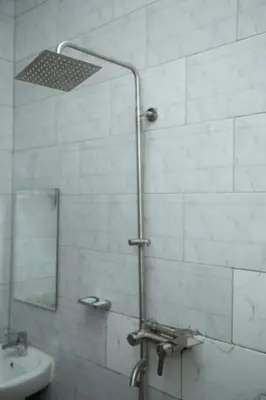 a bathroom with a shower with a sink and a mirror at Randa Family House - Moshi in Himo