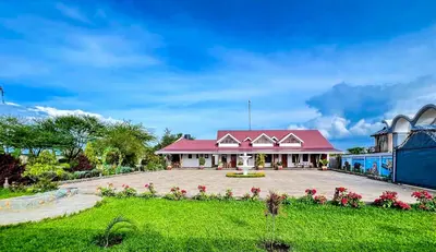a house with a red roof and a green yard at Heart of Africa Lodge in Arusha