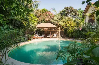 a swimming pool in the middle of a garden at Villa Arumeru in Arusha