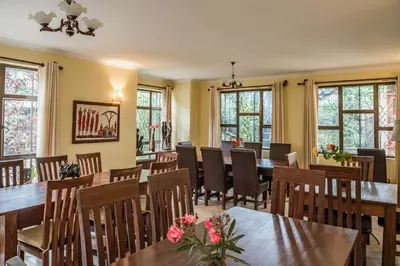 a dining room with tables and chairs and windows at Villa Arumeru in Arusha