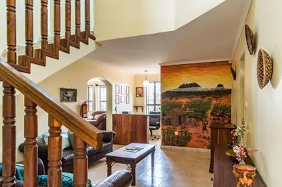 a living room with a staircase with a painting on the wall at Villa Arumeru in Arusha