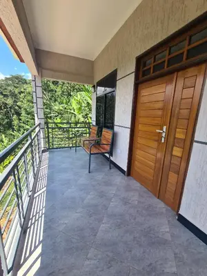 a balcony with a wooden door and a bench at Materuni Homes in Moshi
