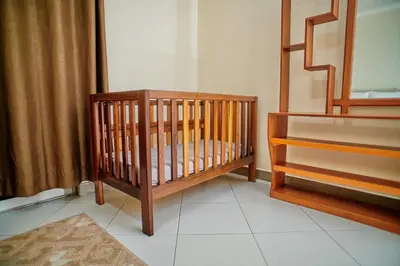 a crib sitting in a room next to a curtain at Hil Venture in Arusha