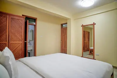 a bedroom with a white bed and a mirror at Hil Venture in Arusha