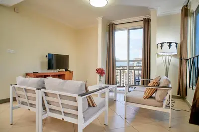 a living room with white furniture and a large window at Hil Venture in Arusha