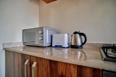 a kitchen counter with a microwave and a tea kettle at Hil Venture in Arusha