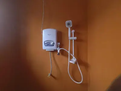 a room with a shower with a hair dryer on a wall at East Homestay in Boma la Ngombe