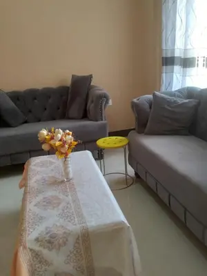 a living room with a couch and a table with flowers on it at B-MORE COMFORT STAY in Boma la Ngombe
