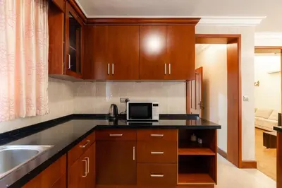 a kitchen with wooden cabinets and a microwave at Kibo Homes Moshi in Moshi