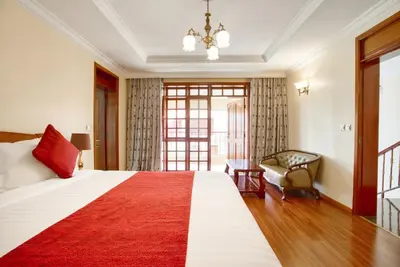 a bedroom with a large bed with a red rug at Kibo Homes Moshi in Moshi