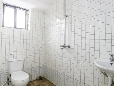 a white tiled bathroom with a toilet and a sink at Arusha Safari Hostel in Arusha