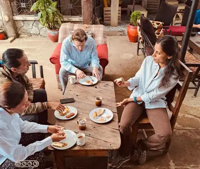 a group of people sitting around a table eating food at Arusha Safari Hostel in Arusha