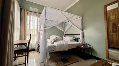 a bedroom with a canopy bed with white sheets at Medan Apartments in Arusha