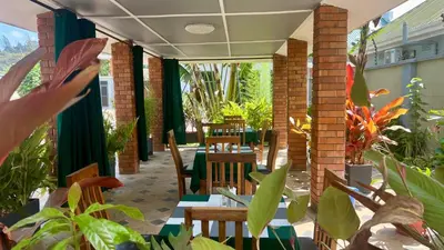 an outdoor patio with tables and chairs and plants at Medan Apartments in Arusha