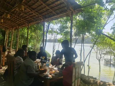 a group of people sitting at a table by the water at Holiday cottage by the river, Arusha in Arusha