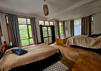 a bedroom with two beds and large windows at Holiday cottage by the river, Arusha in Arusha