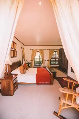 a large bedroom with a bed and a chair at The Manor at Ngorongoro in Karatu