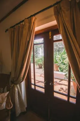 a door with curtains in a room with a patio at The Manor at Ngorongoro in Karatu