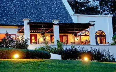 a white house with two lights on the lawn at The Manor at Ngorongoro in Karatu