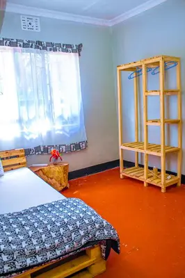 a bedroom with a bed and a window and a shelf at Arusha Jua Eco Home- on coffee farm in Arusha