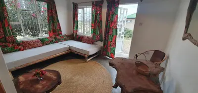 a room with a couch and a table and windows at Africa Amini Homes - Africa Amini Life in Nkoaranga