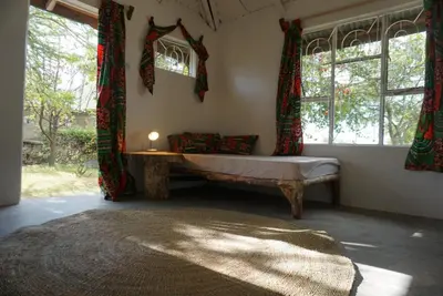 a room with a bed and a window with a candle at Africa Amini Homes - Africa Amini Life in Nkoaranga