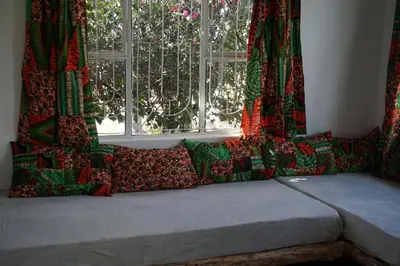 a couch with pillows in front of a window at Africa Amini Homes - Africa Amini Life in Nkoaranga