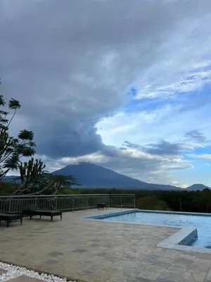 a pool with benches and a view of a mountain at Forest Hill Hotel in Arusha
