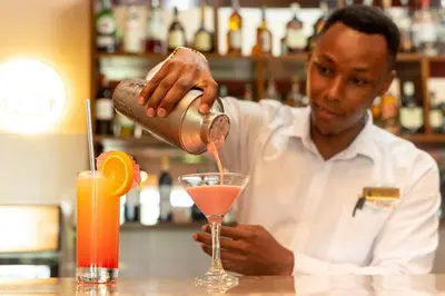 a man is making a drink at a bar at Forest Hill Hotel in Arusha