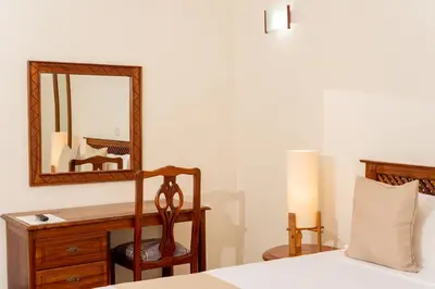 a bedroom with a dresser and a mirror and a bed at Forest Hill Hotel in Arusha