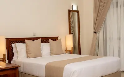 a bedroom with a large bed and a mirror at Forest Hill Hotel in Arusha